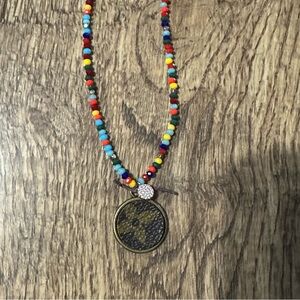 Upcycled charm on a multi colored beaded necklace with a tiny circle rhinestone